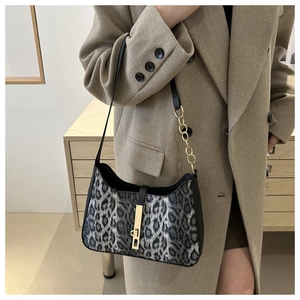 Detailed view of leopard print shoulder bag with gold chain strap and buckle closure
