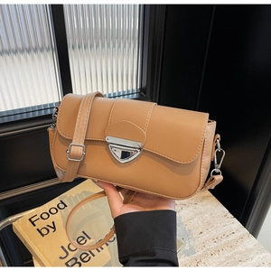 Gros plan d'un sac bandoulière marron chameau avec boucle métallique triangulaire