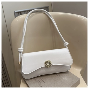 Close-up of a white underarm bag featuring a golden swirl buckle and knot handle detail