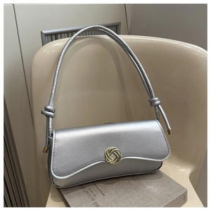 Detail of silver metallic shoulder bag with golden intertwined knot clasp on a flap cover