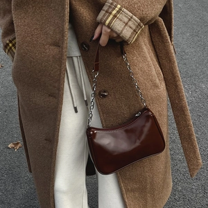 Glossy brown baguette bag with silver chain strap shown in a street fashion style