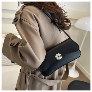 Detail of minimalist black matte shoulder bag with golden round buckle and knot strap detail