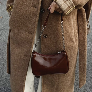 Detail of dark brown patent leather shoulder bag with glossy finish and silver chain strap