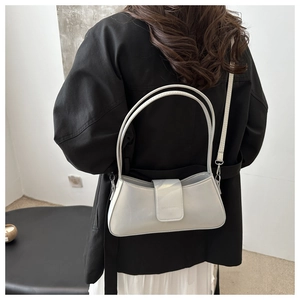 Detail of silver glossy baguette bag with double straps worn by model in casual style