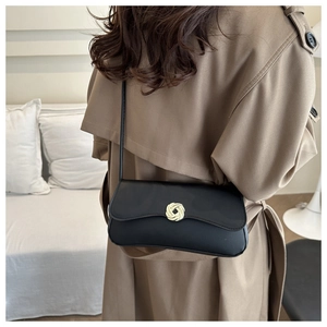 Detailed view of black matte leather shoulder bag featuring a golden circular woven lock