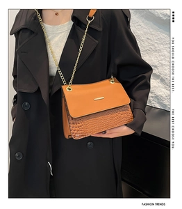 Close-up of brown crocodile embossed leather shoulder bag with gold chain strap