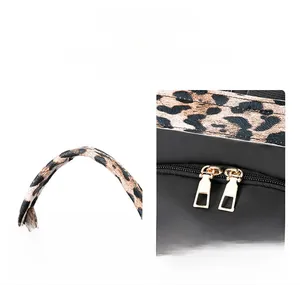 Detail of leather handle and smooth gold double zippers on leopard pattern backpack