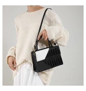 Detail of contrast color crossbody bag showing croc-embossed texture on model
