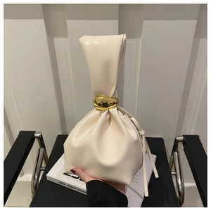 Detail view of cream bucket bag with elegant pleats and golden metal ring hardware