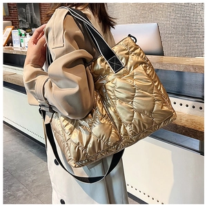 Detailed view of gold quilted puffer tote bag with black and white striped shoulder strap