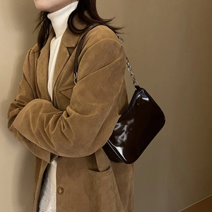 Detail view of dark brown patent leather underarm bag with silver metal chain strap