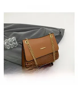 Detail of brown shoulder bag showing faux crocodile texture and gold chain strap