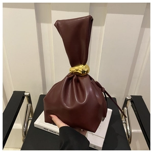 Close-up of a burgundy leather bucket bag featuring a unique gold metal ring handle detail