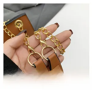 Close-up of brown leather shoulder strap with gold metal chain and lobster clasp detail