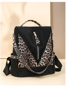 Detail of leopard print nylon backpack showing golden zippers and side storage pockets