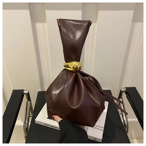 Detail of dark chocolate pleated bucket bag featuring a large decorative gold metal ring