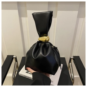 Close-up of black pleated leather bucket bag with an artistic golden egg-shaped buckle