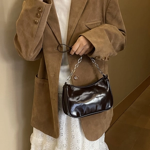 Detail of a dark brown glossy half-moon bag with silver metal chain and leather strap