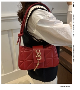 Detail of red quilted leather shoulder bag with golden tassel hardware on white shirt