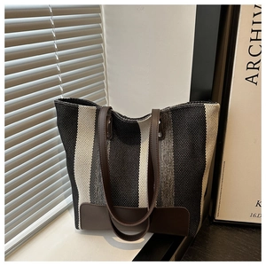 Detail of striped canvas tote bag showing textured weave and premium leather handles