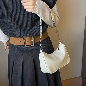 Detail of cream white half-moon underarm bag with silver chain strap worn by a model