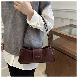 Detailed close-up of dark burgundy baguette bag with glossy finish and brand buckle