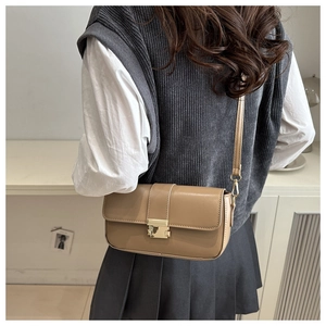 Detail of khaki leather shoulder bag with gold metal buckle shown on model