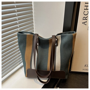 Close-up of vintage striped canvas tote bag with brown faux leather straps and base