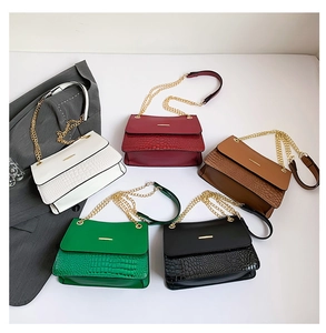 Detailed display of five small square handbags in leather with crocodile texture flap