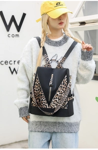 Detail of nylon backpack featuring leopard print straps and side pockets with gold zippers