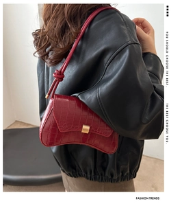Détail du sac baguette rouge effet croco avec bandoulière nouée sur veste en cuir