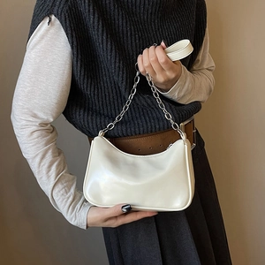 Detail of cream-colored minimalist crescent shoulder bag with silver metal chain strap