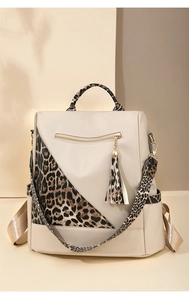 Detail view of cream backpack with leopard print panels and decorative metal tassel