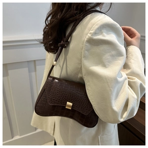 Détail du sac à bandoulière marron foncé en cuir gaufré crocodile et fermoir doré