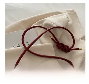 Detail of burgundy leather shoulder bag with quilted stitching and knotted rope strap
