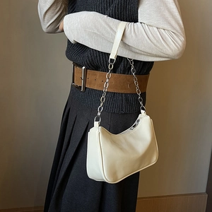 Detail of cream white underarm bag with silver chain strap shown on a fashion model