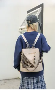 Back view of khaki leopard print backpack with tassels on stylish urban background
