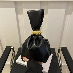 Minimalist black pleated bucket bag with a distinctive gold metal pebble buckle detail
