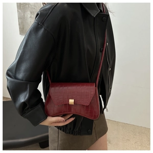 Détail du sac à bandoulière rouge foncé avec motif crocodile et fermoir doré élégant