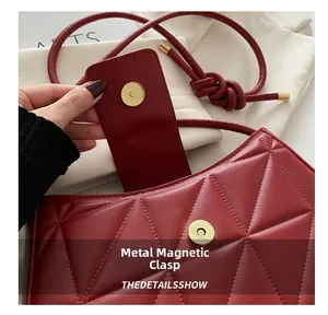 Detail of red quilted crescent bag showing the gold magnetic hardware clasp closure