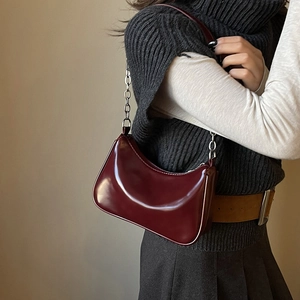 Close-up of a glossy burgundy patent leather shoulder bag with silver metal chain strap