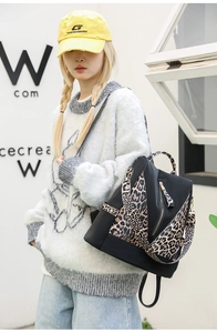 Detail of black nylon backpack with leopard print straps and gold zipper accents