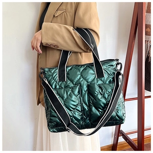 Macro shot of green quilted tote showing glossy fabric texture and striped handle detail