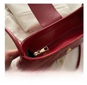 Detail view of red quilted crescent bag with smooth gold zipper and luxury leather texture