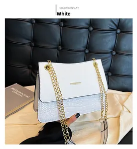 Detail of white crocodile embossed leather bag with gold chain strap and flap closure