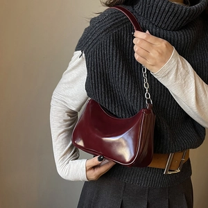 Detail of dark burgundy high-gloss shoulder bag with silver chain and leather strap