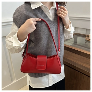 Side view of a bright red leather baguette shoulder bag with embossed logo detail