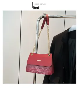 Detail of red shoulder bag featuring crocodile texture and gold chain strap accent