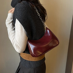 Detail of burgundy glossy leather hobo bag with sleek silver metal chain strap