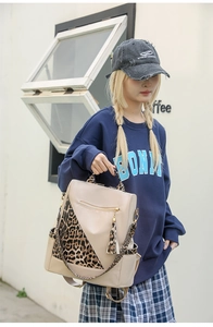 Close-up of stylish faux leather backpack with leopard print straps and tassel detail